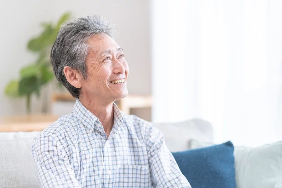 Elderly man smiles while relaxing at home on the couch following an apicoectomy